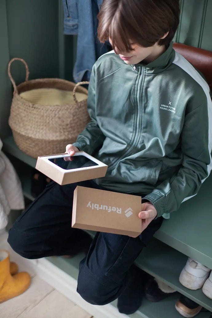 Tonåring öppnar Refurbly mobillåda med begagnad mobil i