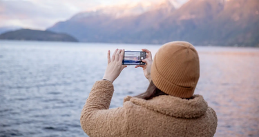 Kvinna fotograferar havet med mobil