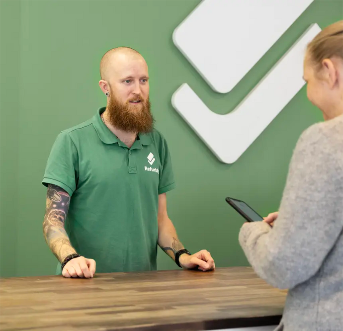 Glad personal bakom disken i Refurbly Store tar emot en kund